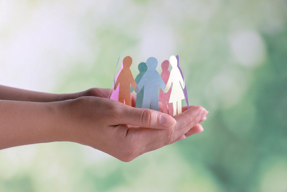 Business Ethics and Compliance - Respect for Human Rights Close-up of hands holding human paper figures, set against a blurred background. This image illustrates the concept of diversity and inclusion. In the business ethics of weba Werkzeugbau, this image symbolizes the policy for upholding human rights and compliance with labor regulations.