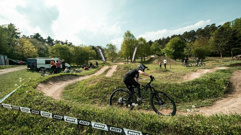 Radek Šimek fährt mit Helm und Mountainbike über eine kurvige Dirt-Strecke beim Training.