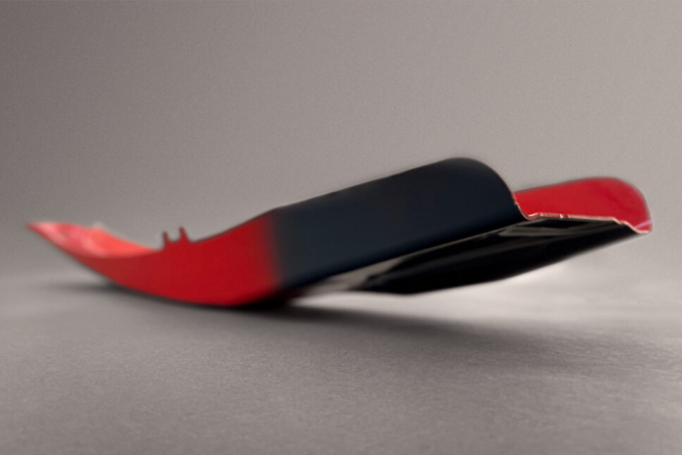 weba Serienfertigung Tailored Tempering Aufnahme einer rotlackierten warmumgeformten B-Säule eines Fahrzeugs, wobei die SoftZone in Anthrazitgrau dargestellt wird. Das Produkt wurde in der Serienfertigung bei weba Werkzeugbau produziert.