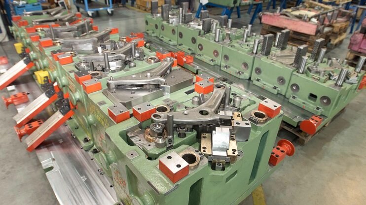 Transferový nástroj pro vahadlo v automobilové výrobě; komplexní upnutí nástroje s několika dutinami formy a mechanickými jednotkami v dílně weba Werkzeugbau.