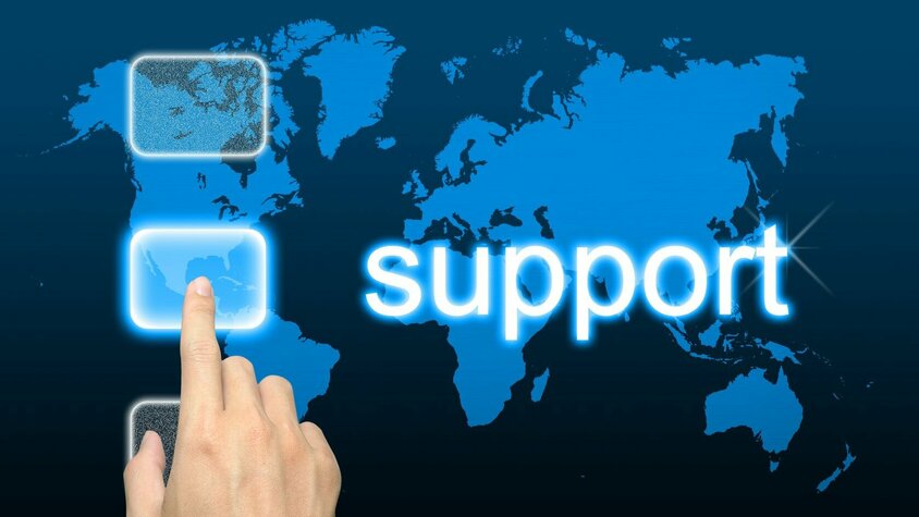 Hand zeigt auf Weltkarte mit „Support“-Schriftzug – Symbolbild für internationalen Kundenservice