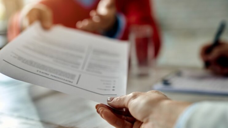 A letter of application is passed from one hand to the other.