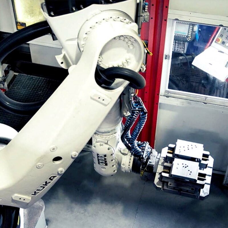 weba Werkzeugbau - Automatisierung in der Zerspanung Ein Roboterarm eines automatisierten 5-Achs Bearbeitungszentrums für Einzelteilfertigung entnimmt Stahlblöcke aus dem Palettenwechsler.