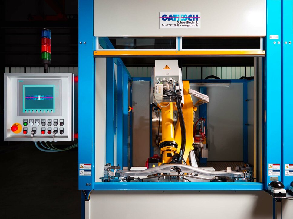 Moderne Automation in der Fügetechnik – Präzision und Effizienz mit Gatzsch Schweißtechnik Eine automatisierte Fügeanlage von Gatzsch Schweißtechnik mit einem gelben Industrieroboter, der präzise Schweißarbeiten durchführt. Auf der linken Seite ist ein Bedienpanel mit einem Display zu sehen, das den laufenden Betrieb überwacht. Die Anlage steht in einer industriellen Produktionsumgebung und symbolisiert den Einsatz moderner Automation in der Fügetechnik.