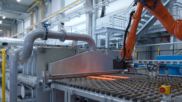 Automatisierte Warmumformungsanlage mit Roboterhandling und glühendem Stahlblech zur Herstellung hochfester Leichtbauteile.