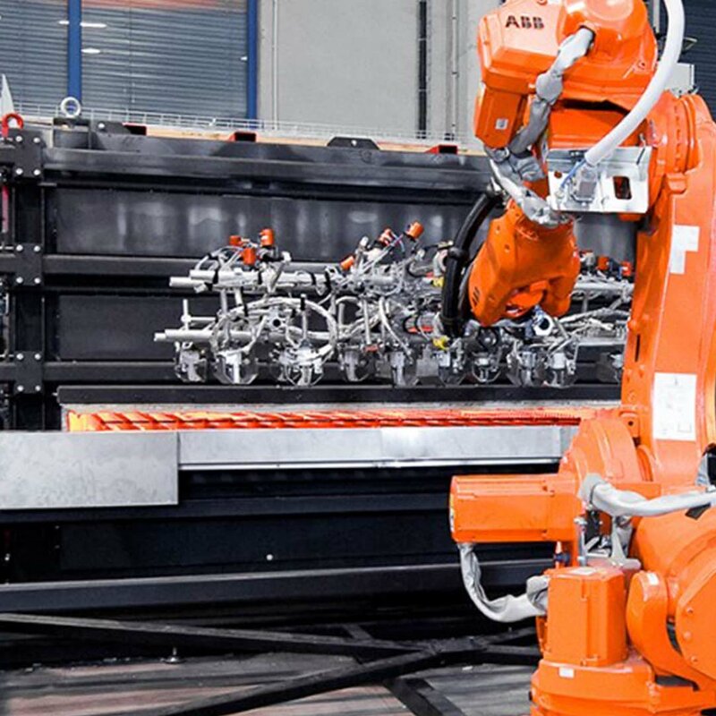 weba Werkzeugbau - Automatisierung des Warmumformprozesses Ein Roboterarm entnimmt vier glühende Formplatinen aus einem Kammer-Warmformofen für den Transfer in die Umformpresse und Bauteilproduktion.