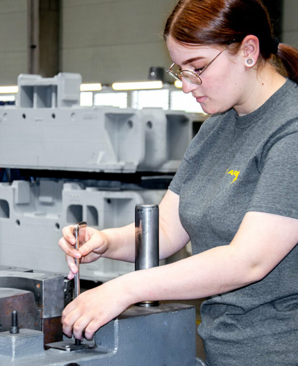 Eine junge Werkzeugbautechnikerin montiert in ihrer Lehre in Steyr bei weba Werkzeugbau Stanzwerkzeuge.