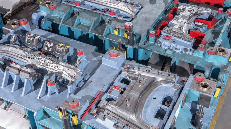 Výřez z linie nástrojů s několika tvářecími a řezacími stanicemi pro tváření karosářských dílů za studena.