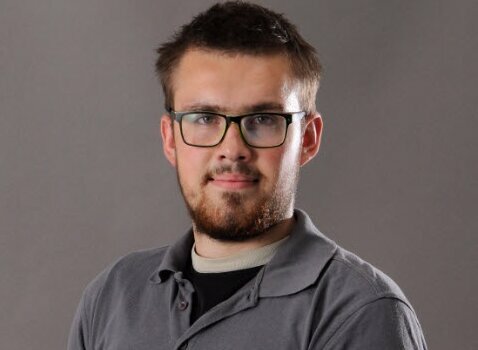 Portrait of toolmaker Jan Wengryn wearing a gray weba polo shirt, smiling confidently in front of a neutral background.