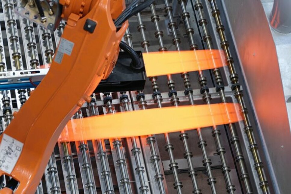 Process Technology for Press Hardening at weba Werkzeugbau An industrial robotic arm positioned in process technology is placing glowing hot metal sheets onto a production line. The use of state-of-the-art technology optimizes the press hardening process and ensures precise control of the forming processes at weba Werkzeugbau.