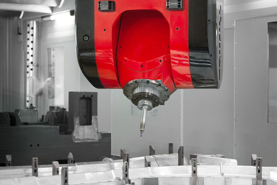 Přesné frézování pomocí CNC technologie ve strojním zpracování Detailní záběr CNC obráběcí hlavy při frézování v mechanickém zpracování. Červenočerná frézovací hlava je přesně umístěna nad upnutým obrobkem. Ostrý řezný hrot nástroje je připraven k vysoce přesnému obrábění, aby vyfrézoval do materiálu složité tvary. V pozadí je vidět interiér CNC stroje, který naznačuje kontrolované a profesionální výrobní prostředí.