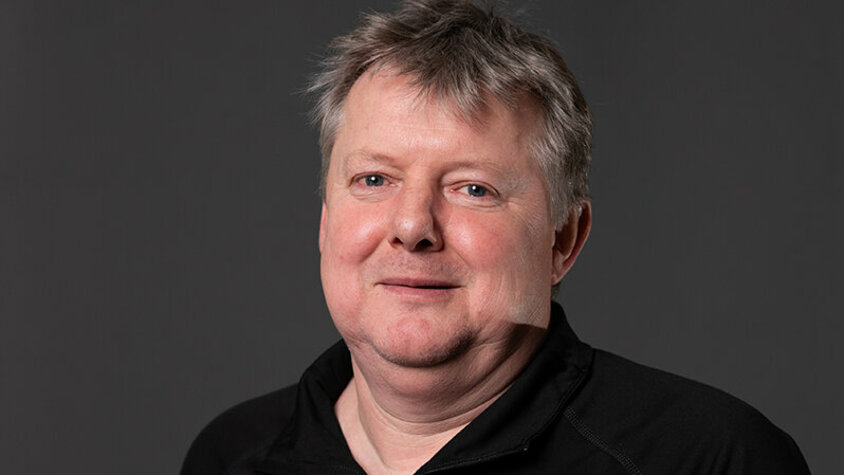 Klaus Postlbauer, Prozessleiter im Werkzeugbau bei weba, lächelt in die Kamera vor neutralem Hintergrund. Mit ruhiger Ausstrahlung und einem leichten Lächeln blickt er in die Kamera. Das Bild vermittelt Kompetenz und Bodenständigkeit – passend zu seiner langjährigen Verbindung mit weba Werkzeugbau.