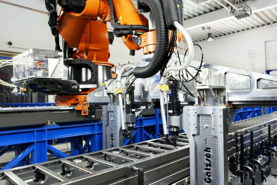 Automatisierte Fügetechnik: Industrieroboter für Nieten und Clinchen Ein moderner Industrieroboter in einer Produktionshalle, der an einer automatisierten Fertigungslinie arbeitet. Der Roboter führt Nieten und Clinchen durch, um Metallkomponenten präzise zu verbinden. Die Anlage ist an einer Förderanlage befestigt und befindet sich in einer hellen, industriellen Umgebung, die für effiziente und präzise Prozesse in der Fügetechnik steht.