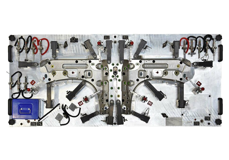 Fixture Construction - Gauge Fixture  A gauge fixture from weba’s fixture construction, photographed from a bird's-eye view, is placed on a flat surface. This perspective provides a complete overview of the fixture, including all markings, scales, and specific features that are essential for the accurate inspection of manufacturing parts. The fixture is precisely engineered, with visible details that highlight its function and application in quality control. Its robust construction and clear arrangement of measurement areas demonstrate high-level engineering expertise. The bird's-eye view captures the overall structure and layout of the fixture, emphasizing its significance and efficiency in industrial metrology.